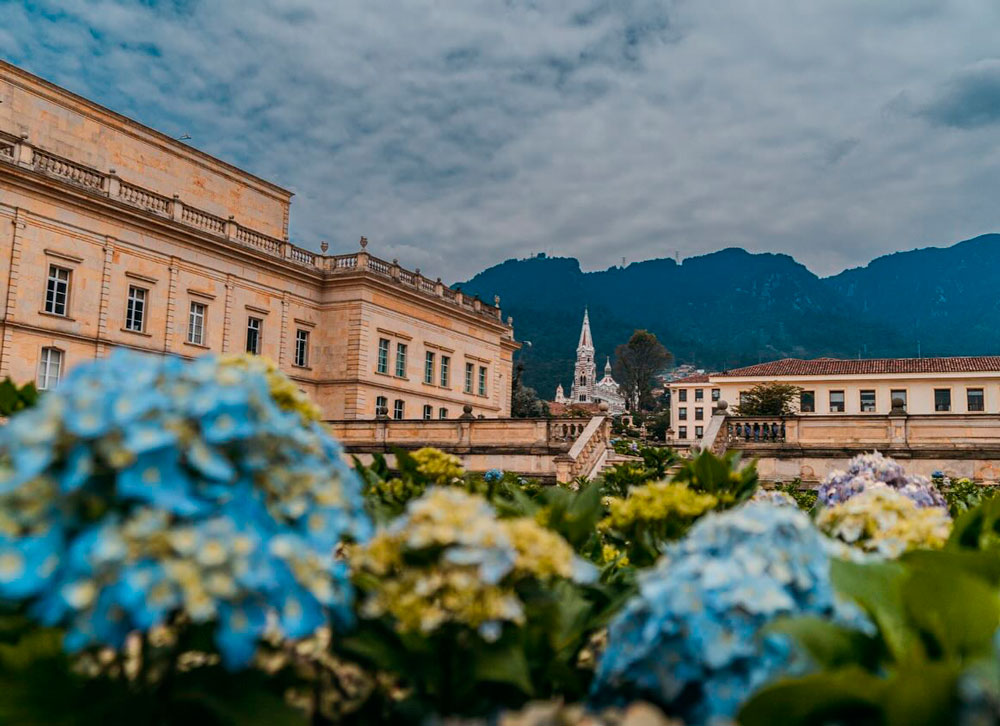 Jardines con hortensias en la Casa de Nariño, vista panorámica de la arquitectura presidencial y los cerros orientales en Bogotá.